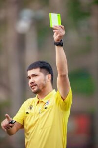 modern soccer referee showing yellow card in packed stadium during World Cup match