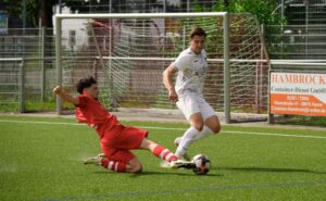 Two footballers in a dynamic sliding tackle on a sunny day during an exciting soccer match.
